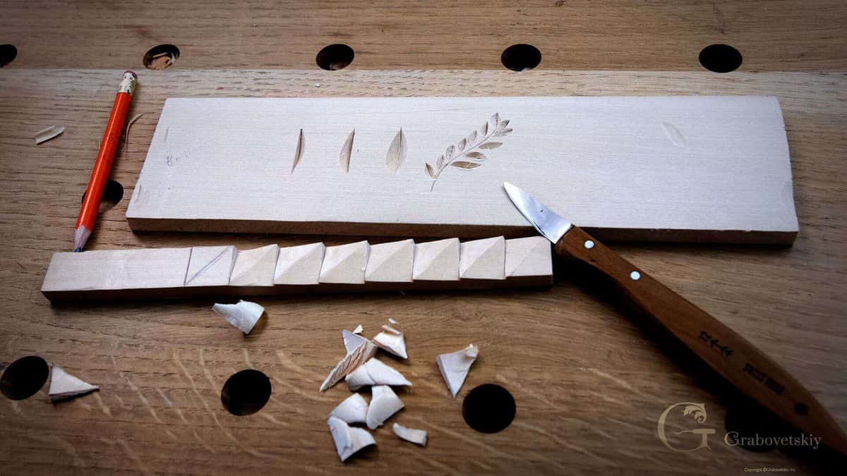 Beginner practice board with leaf shapes, a carved molding strip, a pencil and loose chips