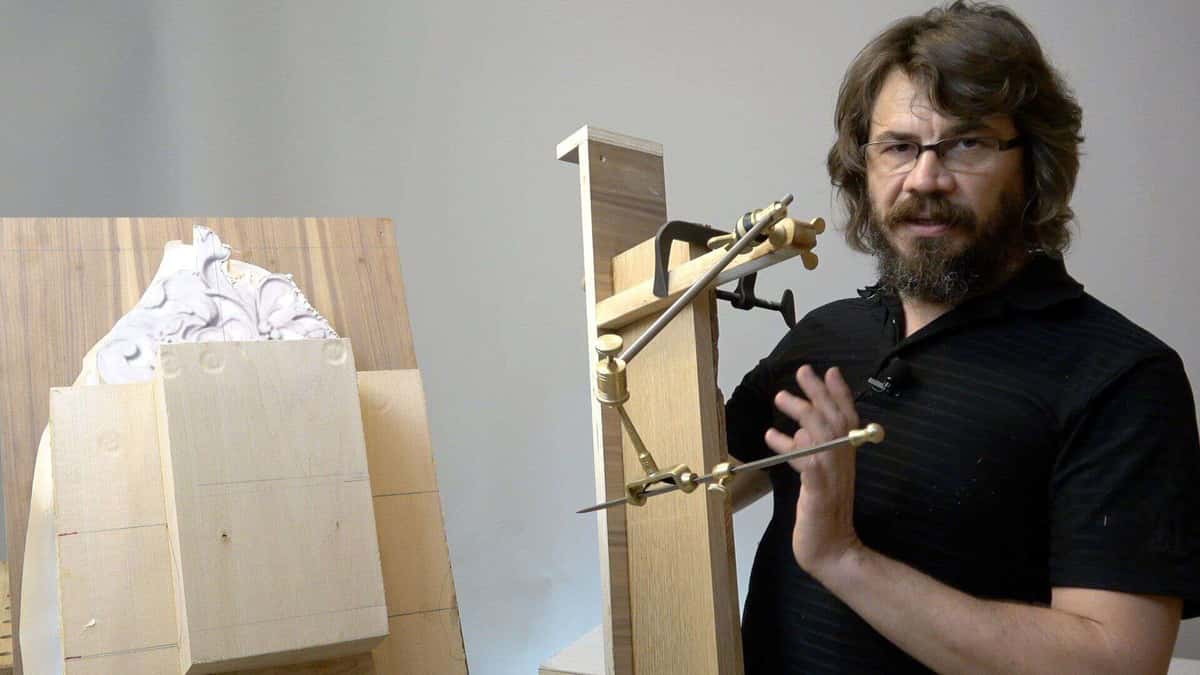 A person demonstrating wood carving techniques in a workshop setting, equipped with various tools like compasses and clamps. Behind them, a workbench displays blocks of wood ready for carving. This scene captures the essence of wood carving classes and hands-on wood carving lessons.