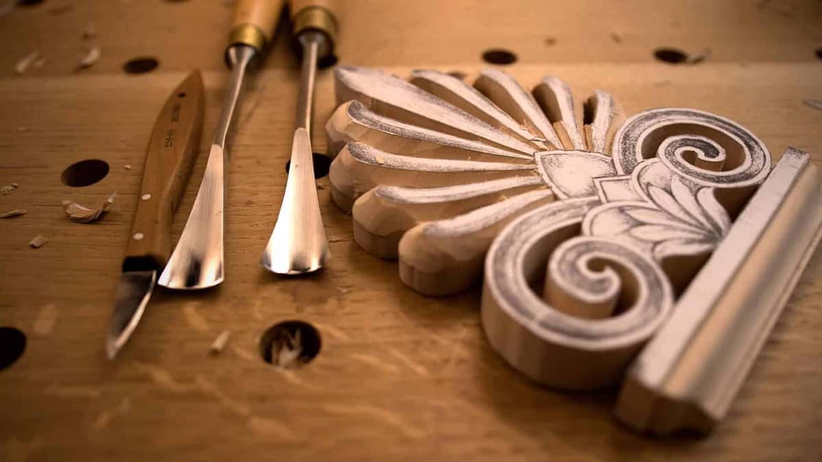 Two spoon gouges and a carving knife on the bench beside a finished acroterion fan