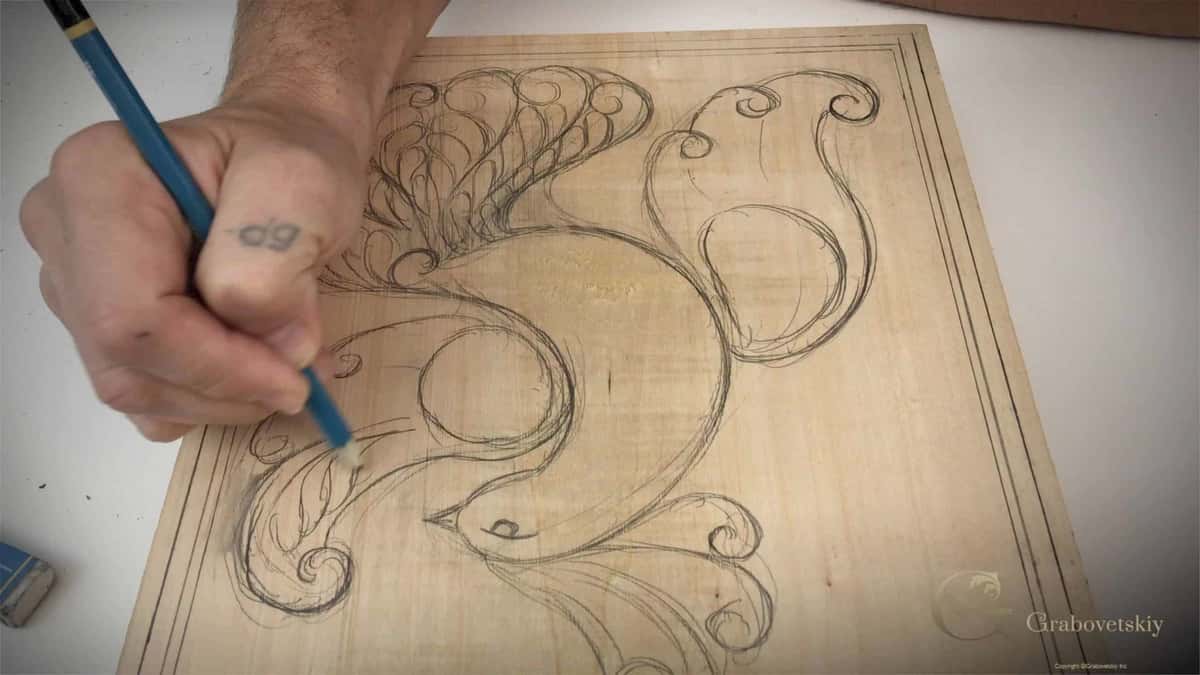 Blue pencil drawing scroll work straight onto a pale carving board