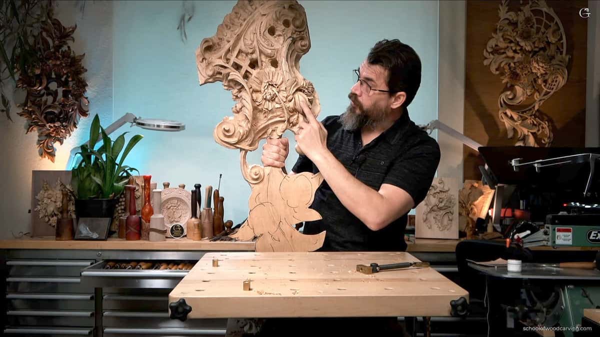A man with a beard is carving a piece of wood.
