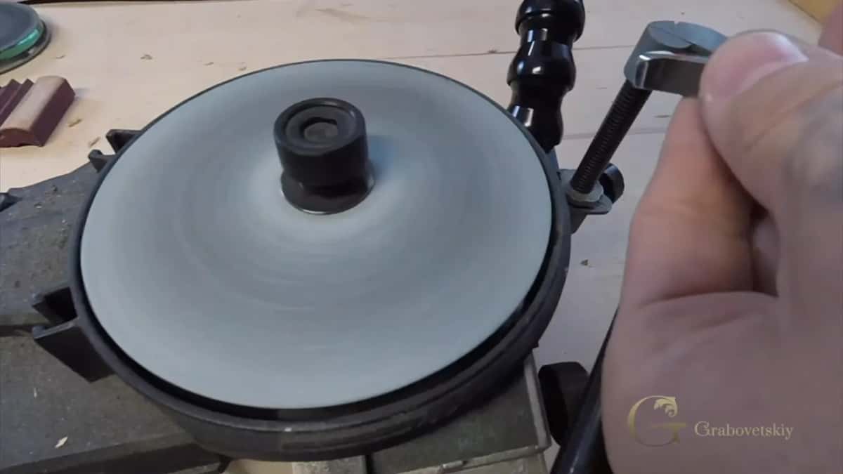 Pale honing disc spinning while fingers turn the black knob that sets the rest