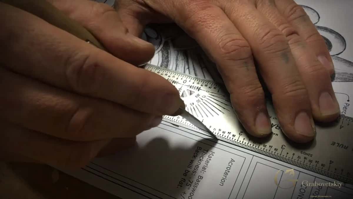 Two hands hold a steel rule flat on a printed plan, the material and thickness notes running along the bottom.