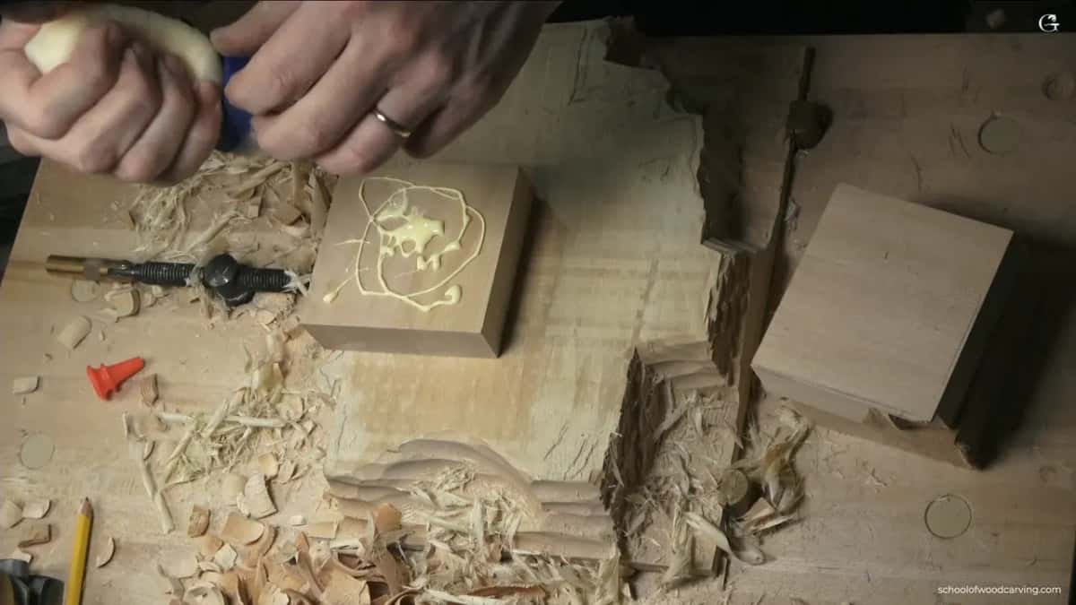 Glue is squeezed in a loose spiral across the flat face of a square block, ready for another block on top.