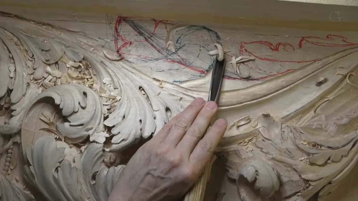 Pressed by hand, a narrow blade works into the acanthus below the red and blue drawing.