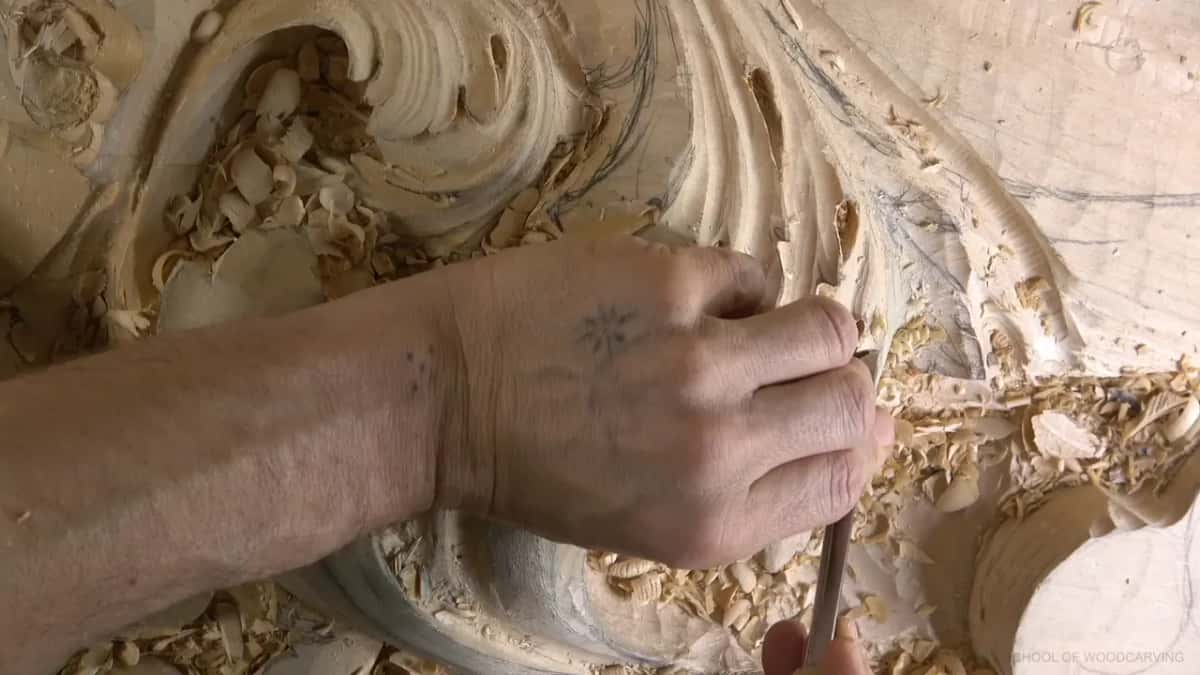 Forearm and hand behind a gouge.