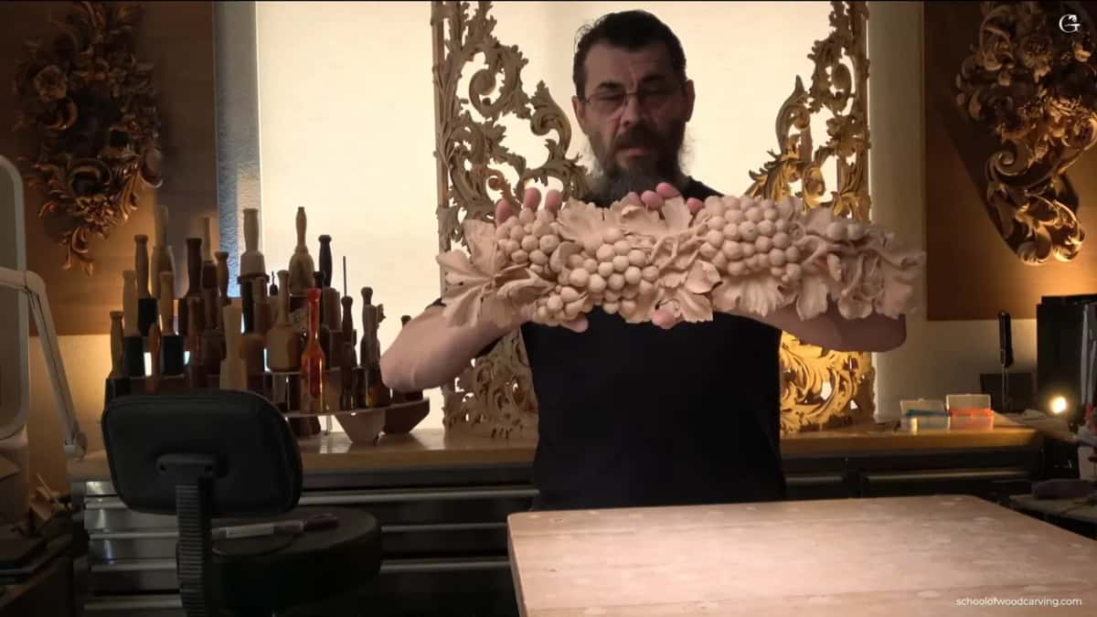 Onlay held up at chest height, carved panels in the shop behind it