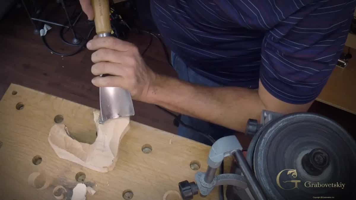 Same gouge driven across the grain, SWISS MADE readable on the handle above his fist.