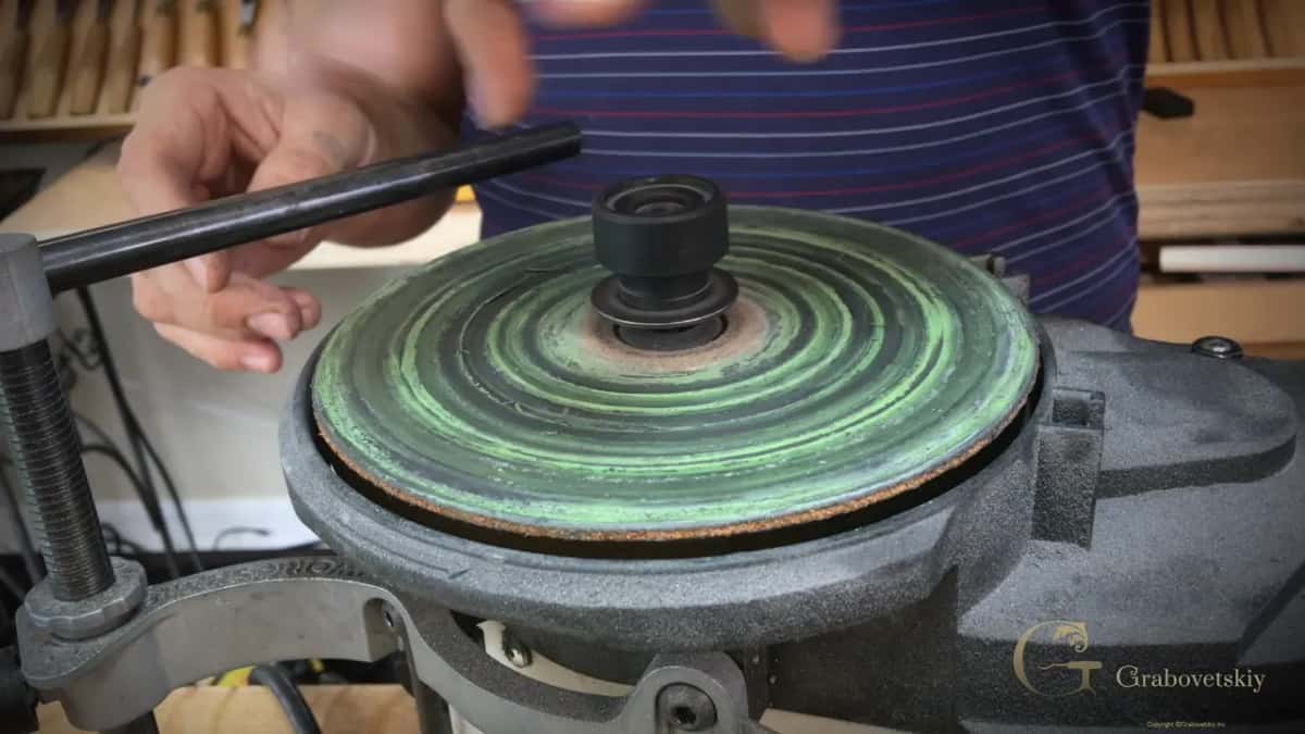 Leather disc caked with green compound, its tan rim showing.