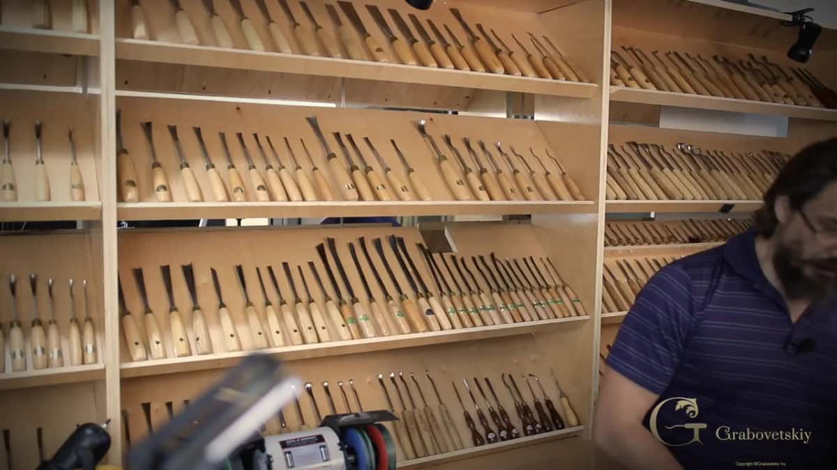 Racks of gouges and chisels filling a shop wall, several hundred handles laid out in rows.