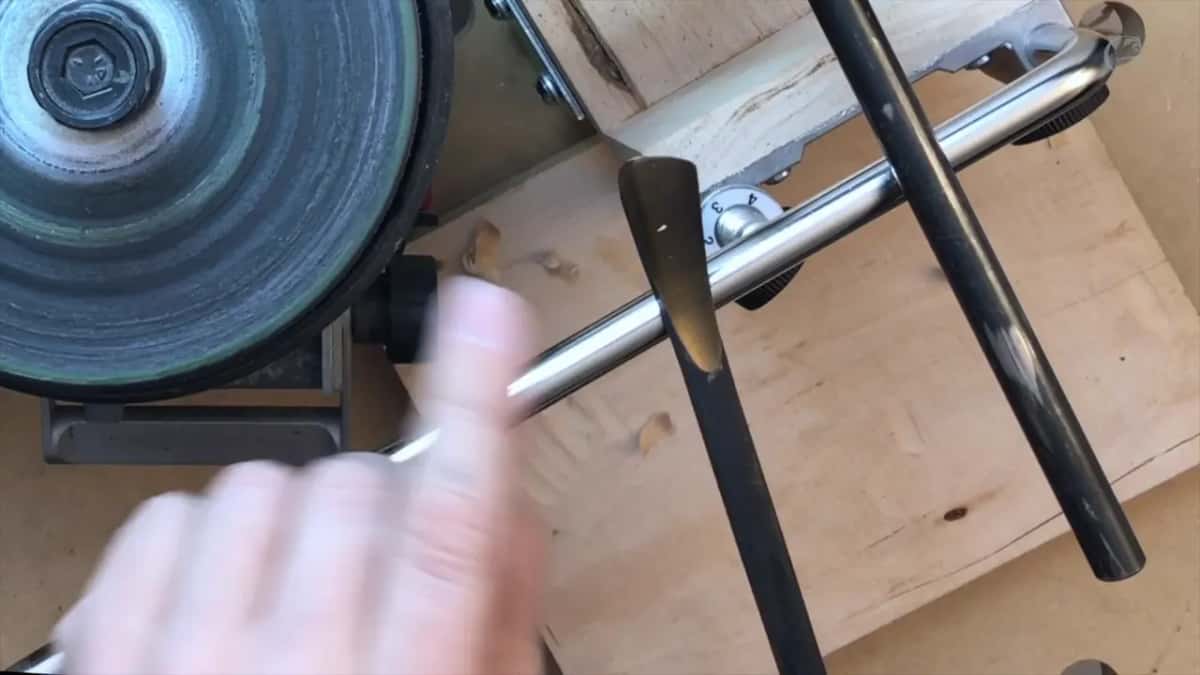 A shaving lifting off plywood ahead of the skewed edge, with curls of wood already on the board.