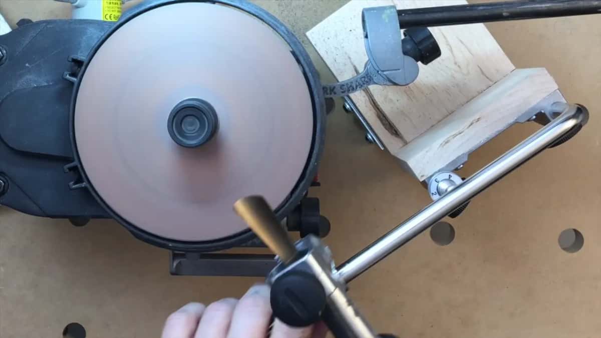 Worn pink disc spinning away, with the tool in its jig coming down towards the surface.