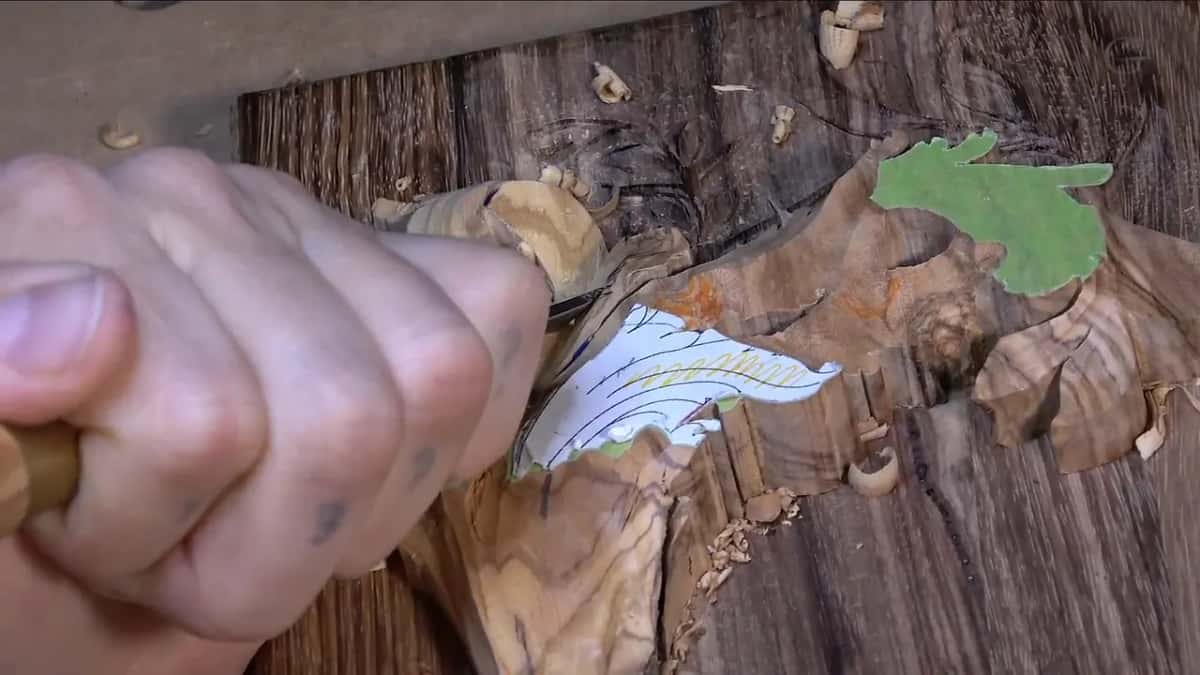 A fist around the handle, slicing a leaf that still wears its paper pattern