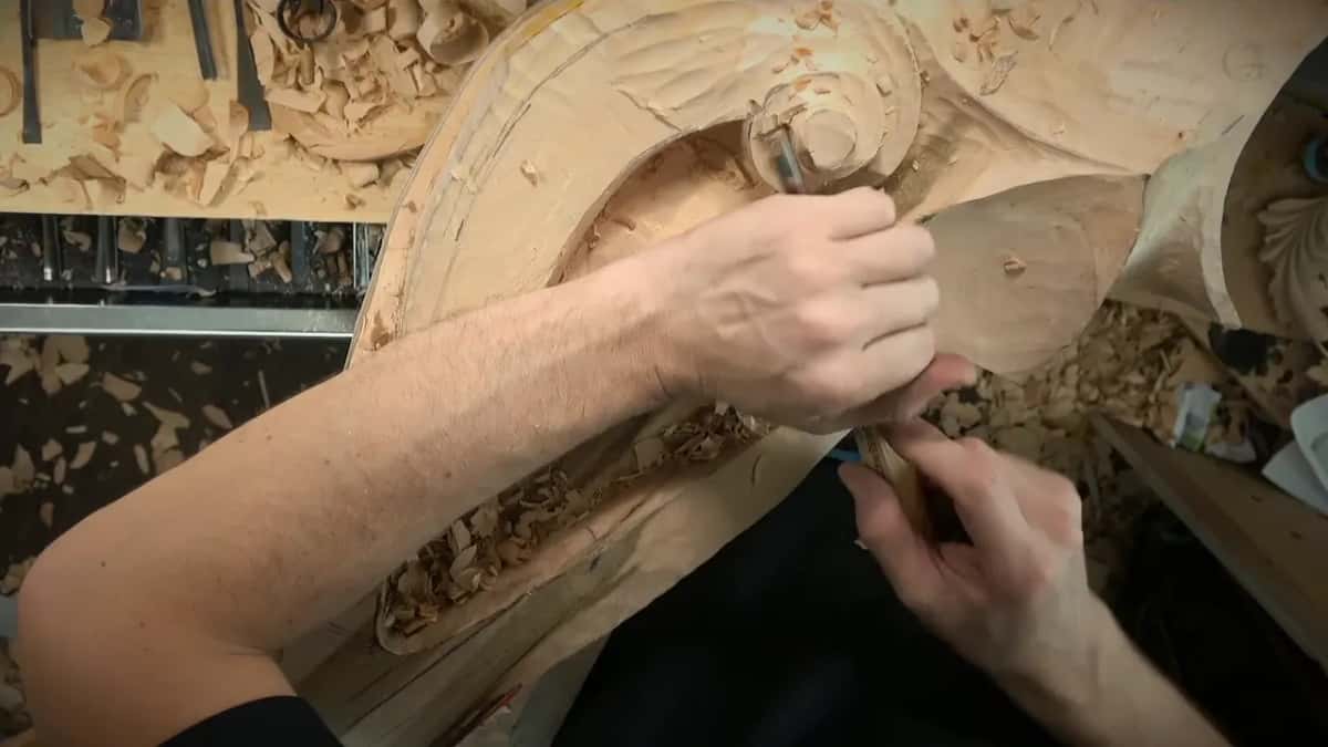 Two hands work a small tool close to the volute's raised ring
