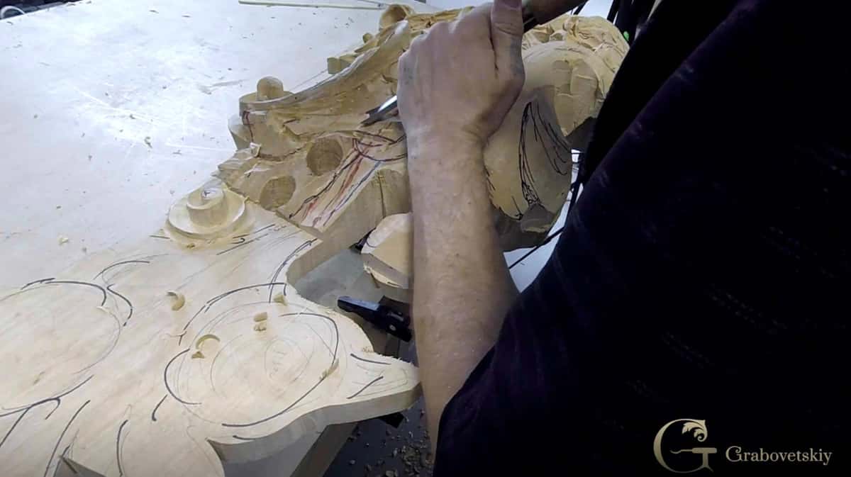 Forms on the bench Carved leaf and shell forms lying on the bench, one hand resting at the near edge