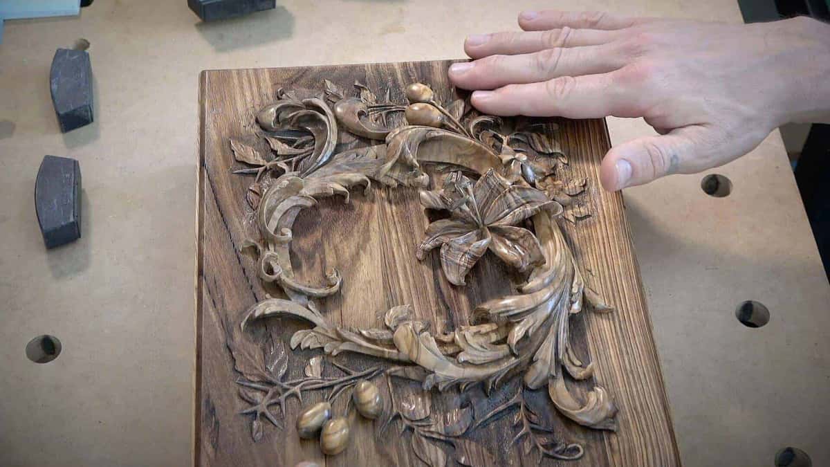 Lily and leaves carved in strongly figured wood where the grain competes with the carved design