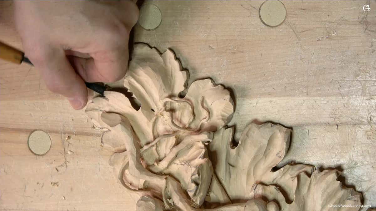 WOODCARVING LESSONS: Woodcarver Grabovetskiy carves a floral pattern in light wood, showing textured leaves and petals for woodcarving tutorials. - Wood Carving tutorials