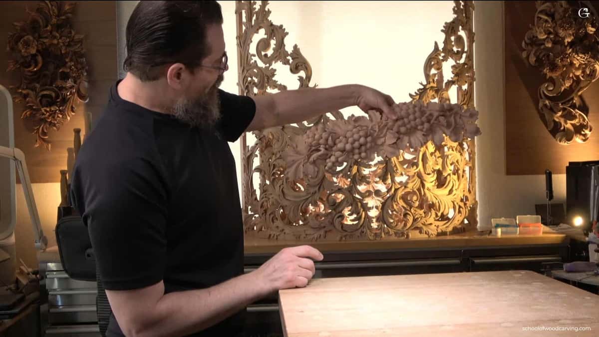 WOODCARVING LESSONS: Woodcarver Grabovetskiy, in glasses and black shirt, holds a grape onlay. More carvings are seen in his bright woodcarving workshop. - Wood Carving tutorials