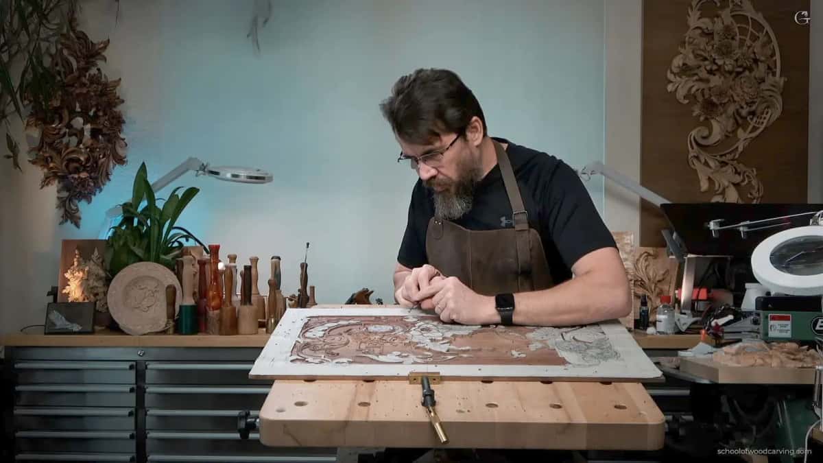 Alexander Grabovetskiy at his bench working on a large carved panel in the studio
