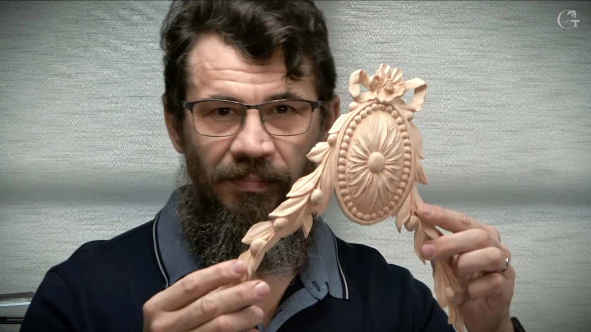 Alexander Grabovetskiy holding up a finished oval rosette with a carved bow