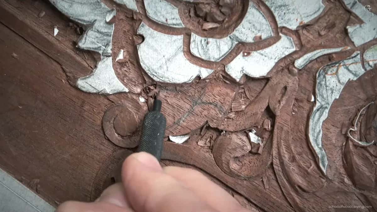 Finding the centre line on an antique carved panel A finger and a small blade on an old painted panel, finding where the raised centre line of the leaf has to run
