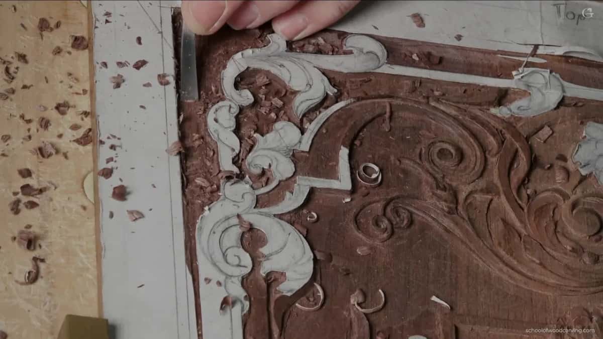 A grounding gouge shaving the background down between the carved elements of a red panel