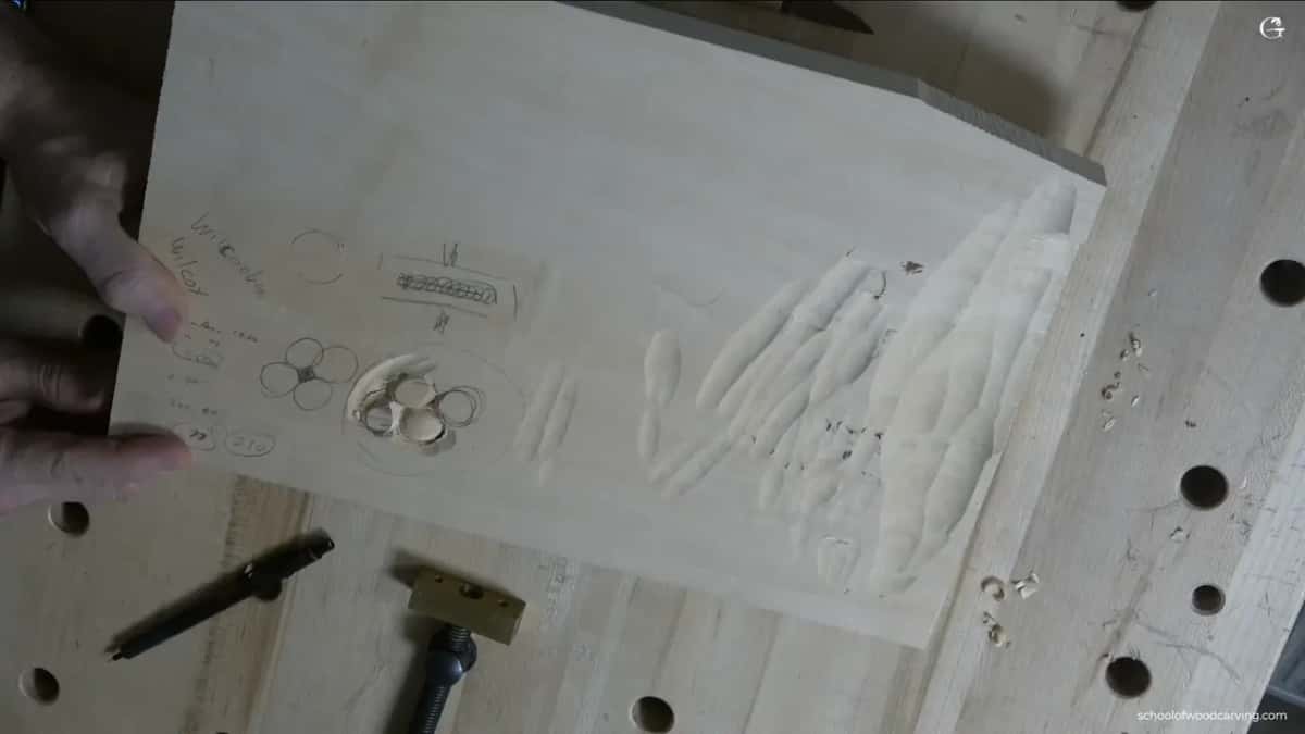 A pale practice board held up to the camera, rows of trial gouge marks on one half and pencil notes on the other.
