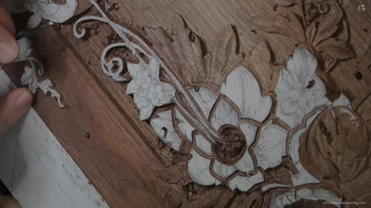 Carved flowers primed white against the brown streaked grain of a dark board.