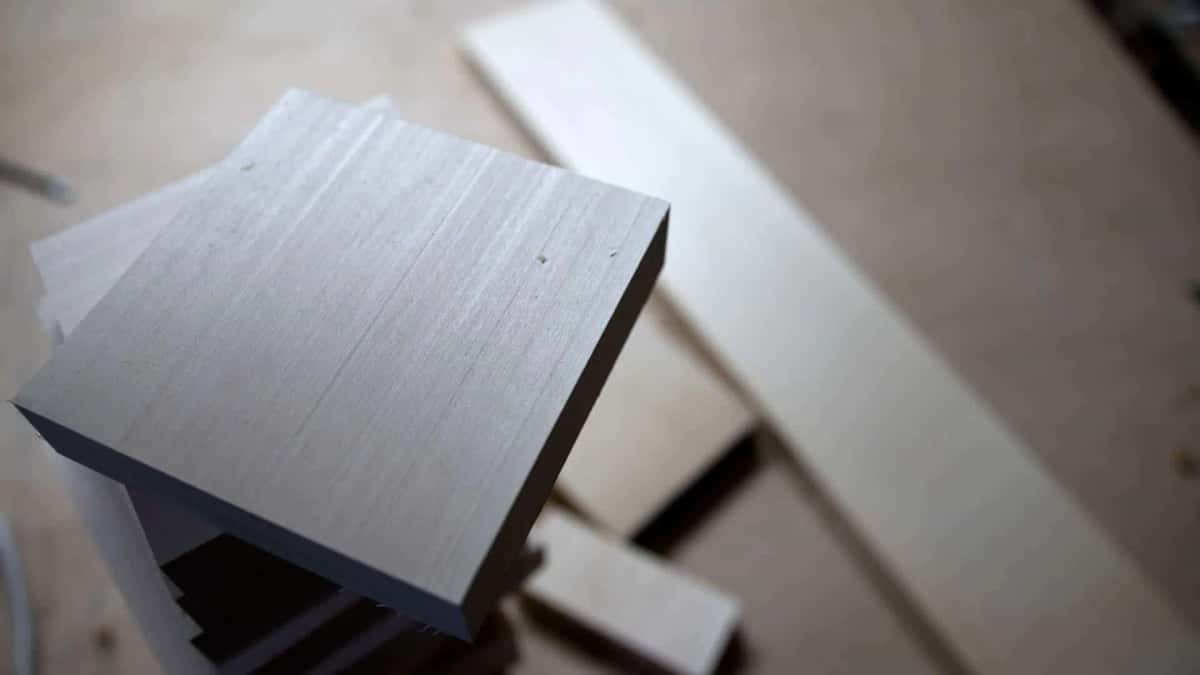 Squared pale basswood blank resting on a workbench with more sawn stock lying behind it