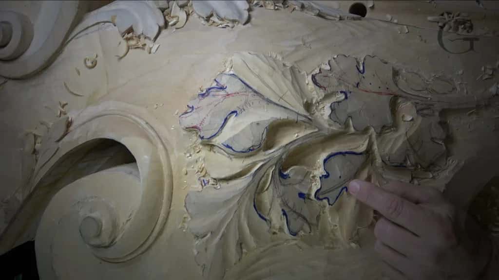 Blue layout marks drawn straight onto a half carved scroll, the way I mark up a shape before committing to it