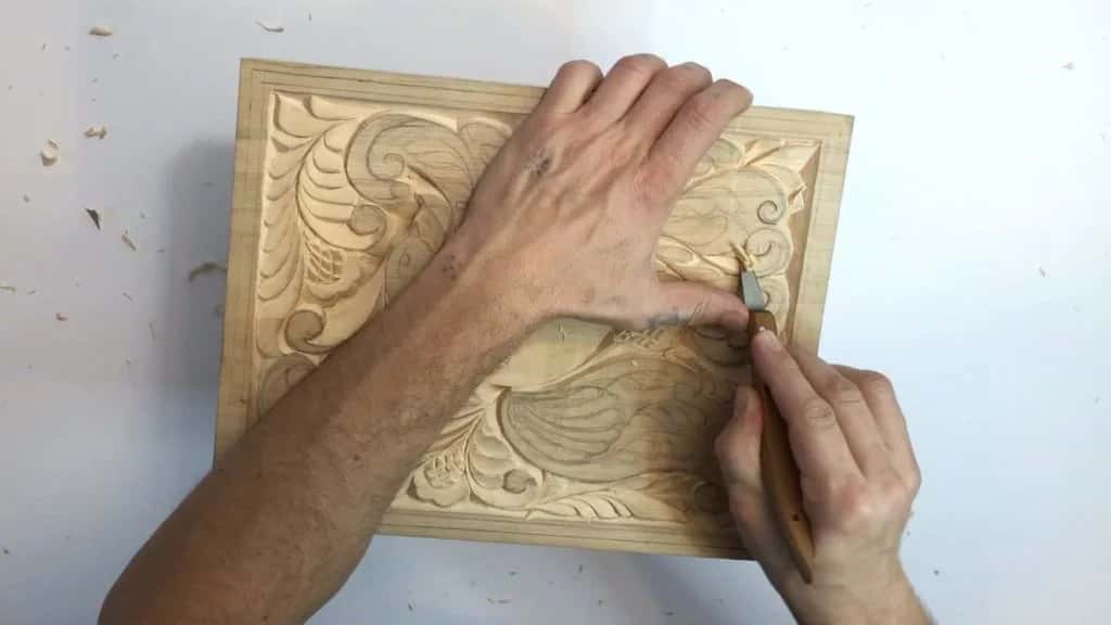 Both hands steadying a beginner panel while the knife works