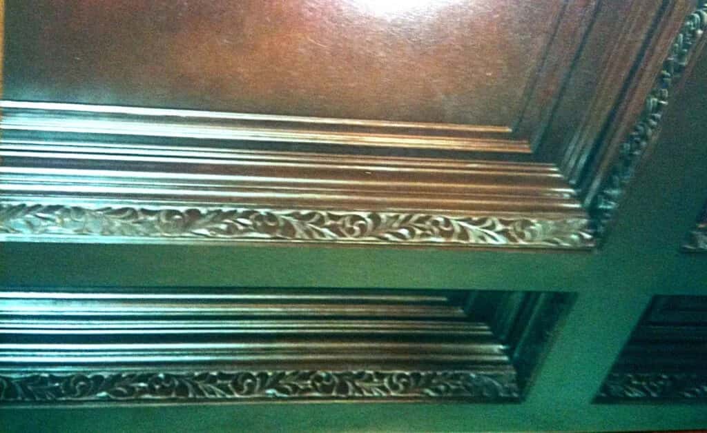 Carved coffered ceiling beams stacked on edge, the run of moulding repeating away from the camera