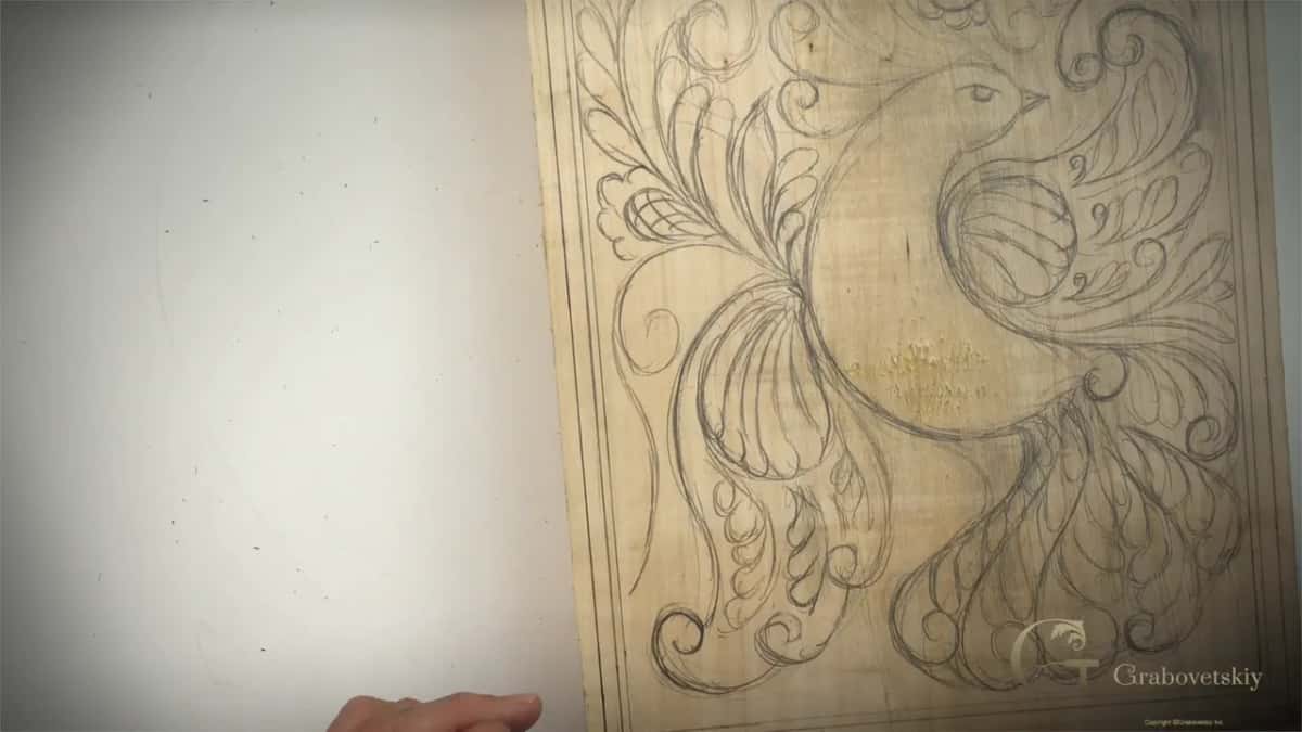 Curls, leaves and flowers filling every space around a carved bird design on a basswood board