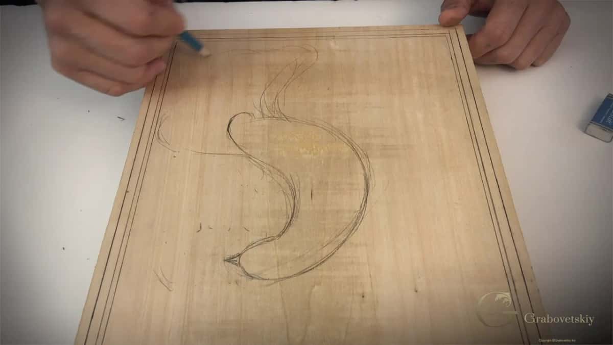 Body and tail of a stylised bird sketched onto a basswood cutting board with an eraser still in hand