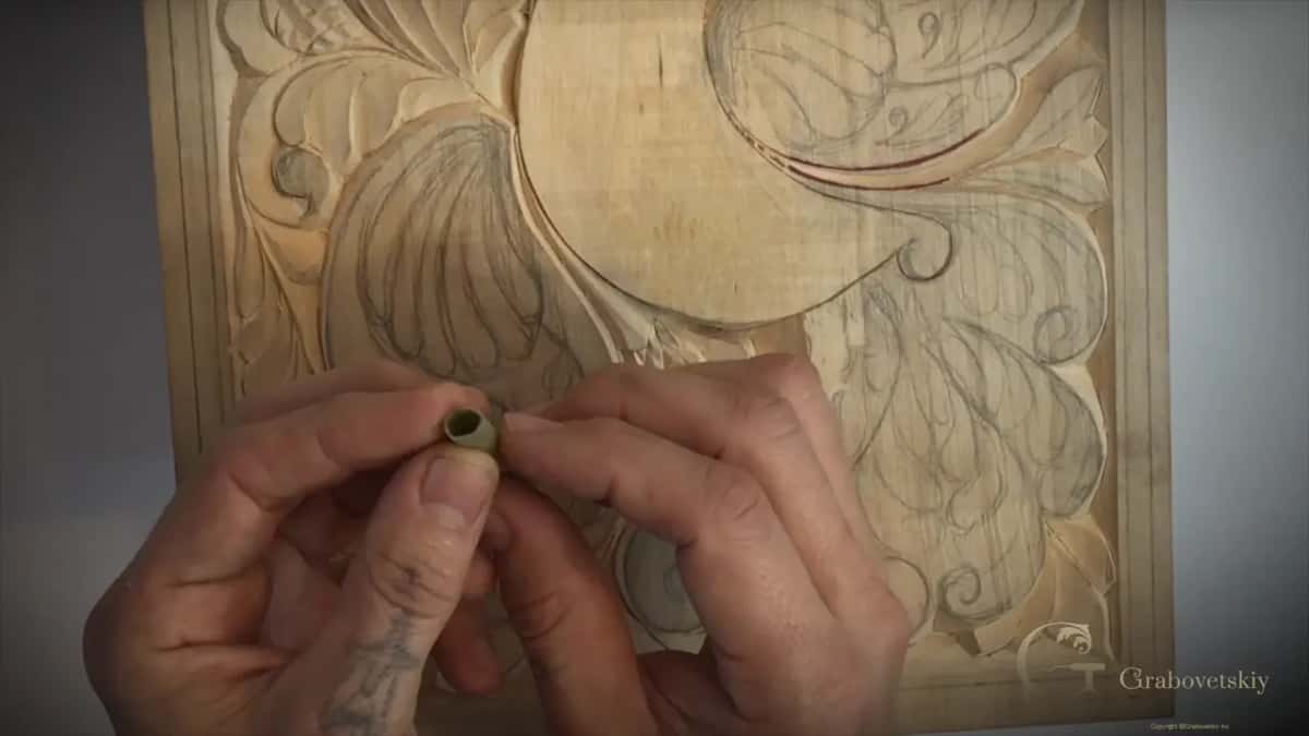 A hollow stalk of Dutch reed held over a half carved board, the natural abrasive used before sandpaper