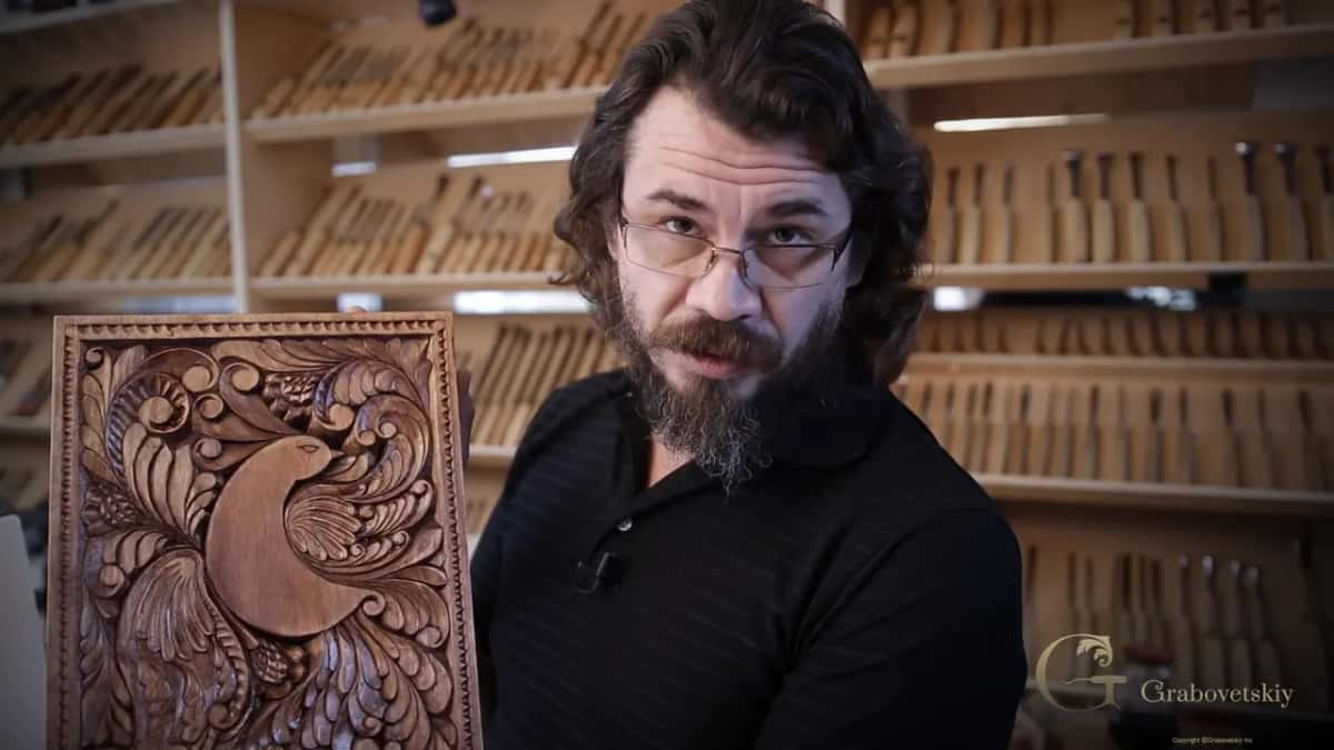 Alexander Grabovetskiy holding a finished dark stained carved board