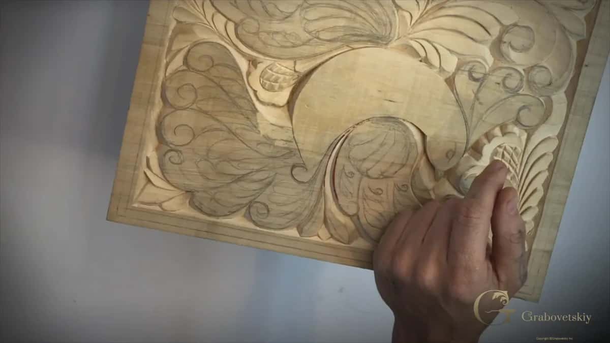 A basswood panel carved in low relief with pencil lines still showing where the carving has not reached