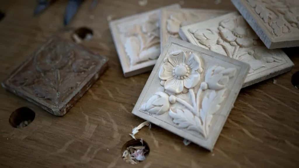 Several carved flower rosette tiles lying together on the bench, some finished and some still rough
