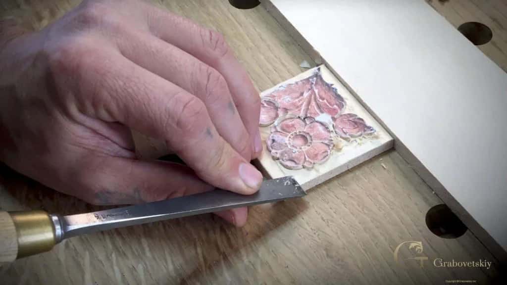A gouge working a small flower rosette tile