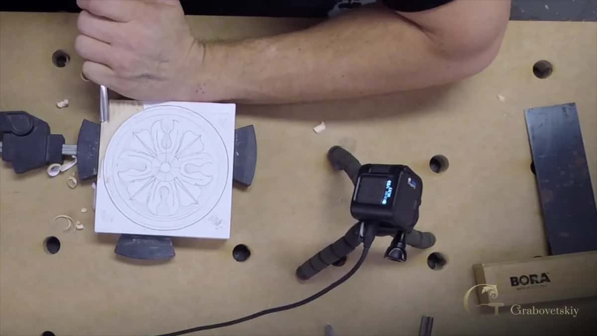 Pattern glued to the block Paper rosette pattern still glued to the block, clamps and a digital gauge around it