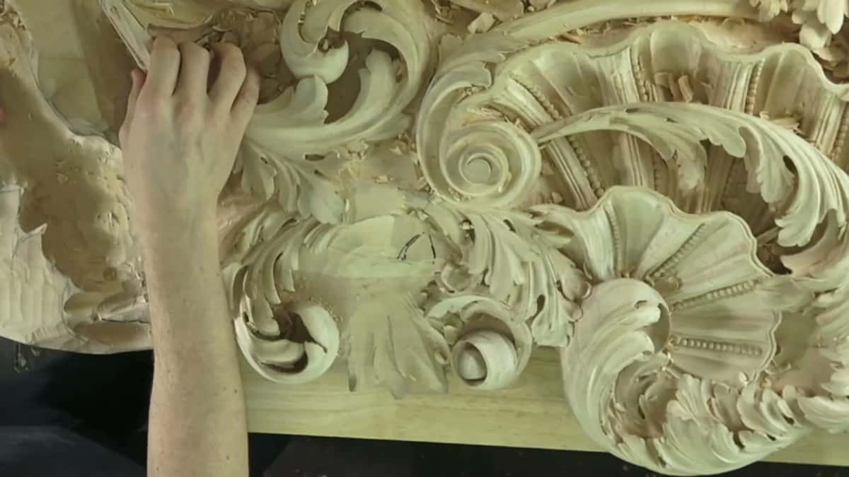 Deeply carved acanthus and a shell in basswood, one hand resting at the panel edge