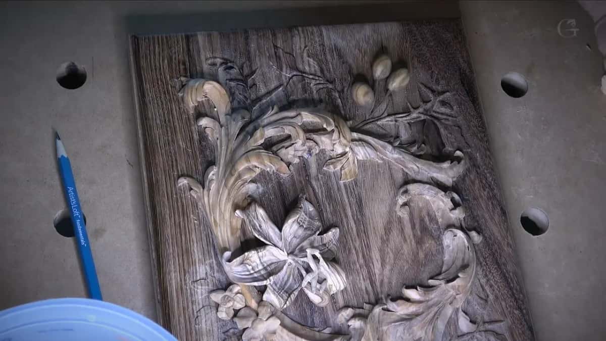 Straight joint lines cross the flat ground of a dark panel carved with a lily and acanthus scrolls.