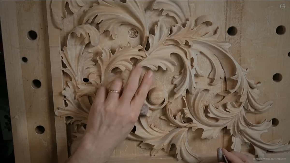 A round plug is set into the ground of a deep acanthus panel, its rough face showing against the carving.