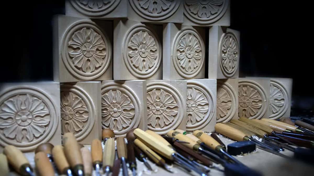 Fifteen carved rosettes stacked on a bench beside the gouges that made them