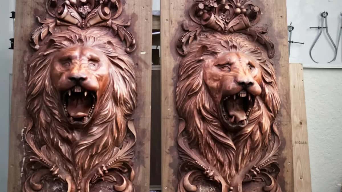 Two matching carved lion head panels standing against a shop wall