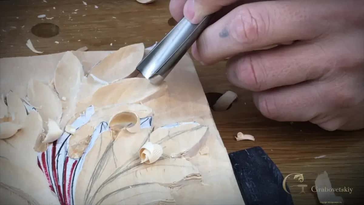 Layout lines surviving into the carving Gouge slicing a leaf while the red and blue layout lines are still on the wood