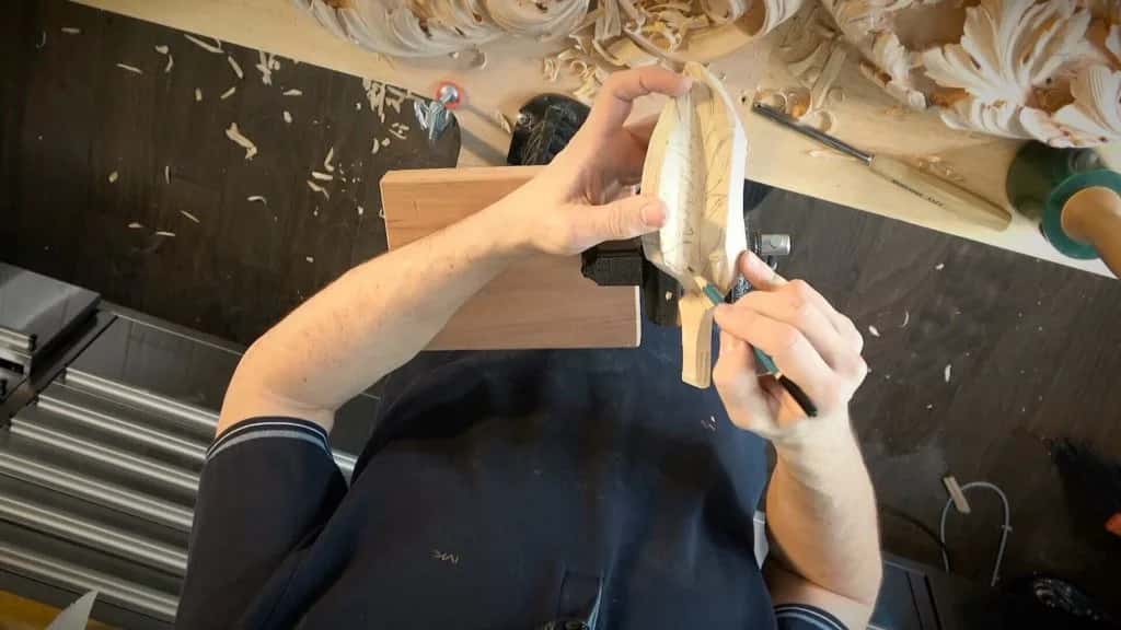 Two hands turning a carved element over above the bench