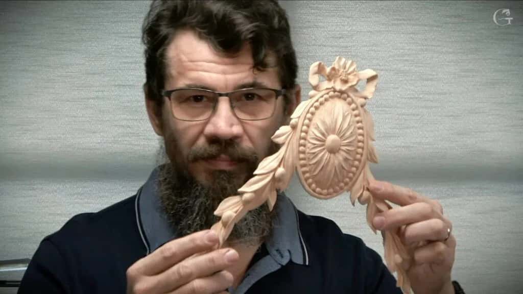 Alexander Grabovetskiy holding a carved rosette up to the camera