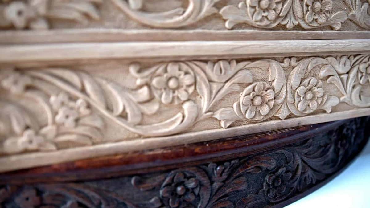 Close on new carved apron sections resting directly on the dark antique table below