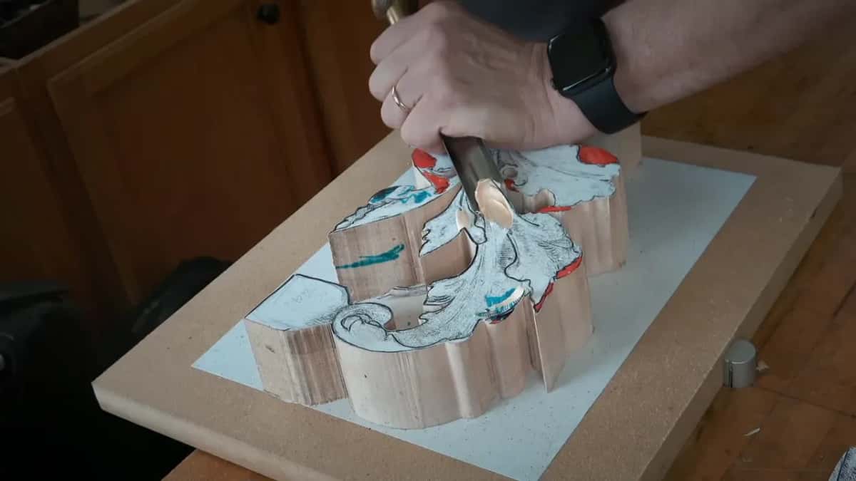 A deep gouge opening the first hollow in a sawn acanthus blank marked with red and teal